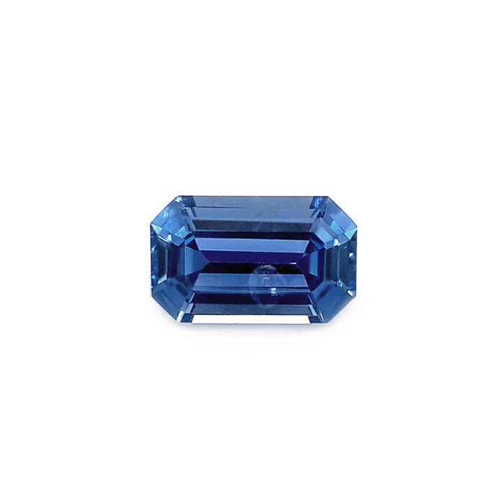 An emerald-cut unheated Yogo sapphire with a mirror-like facets reflecting light, presenting a deep blue color.