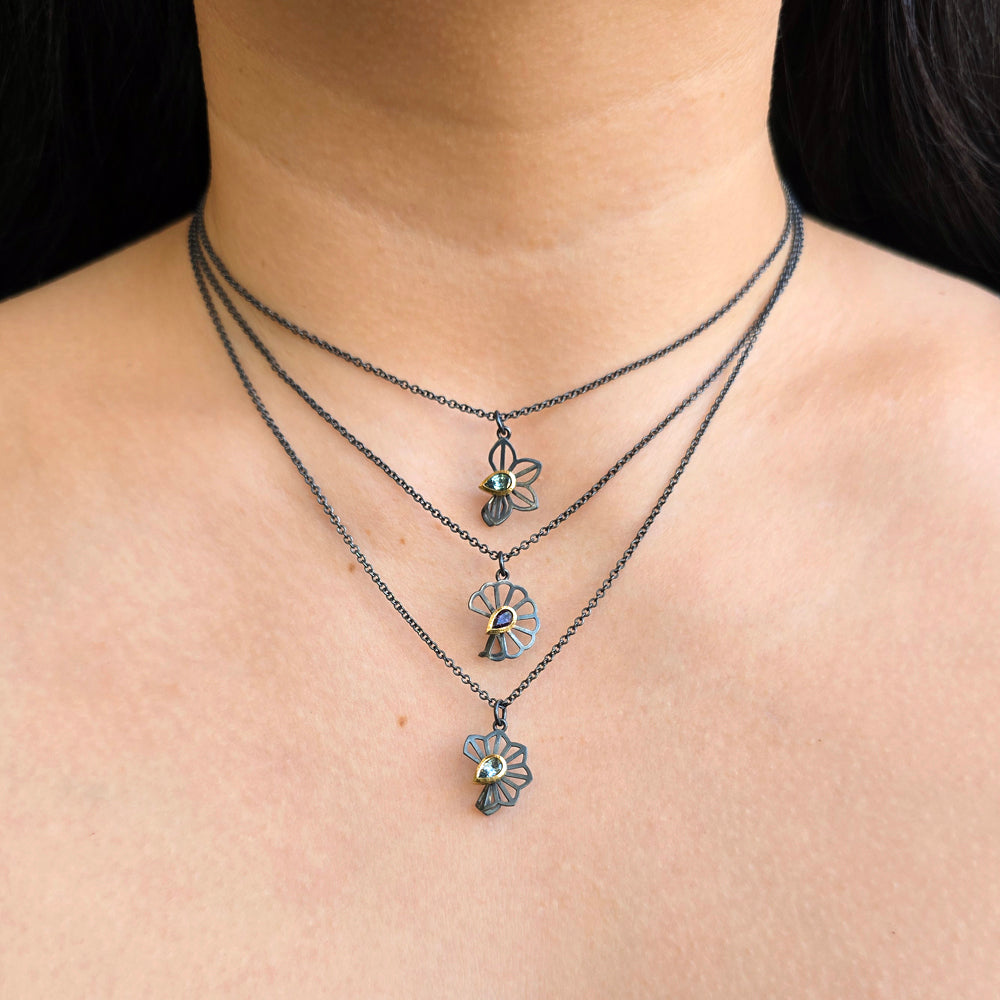 Woman wearing green Montana sapphire Anise Fold necklace and other pendants by Karin Jacobson from Alara Jewelry