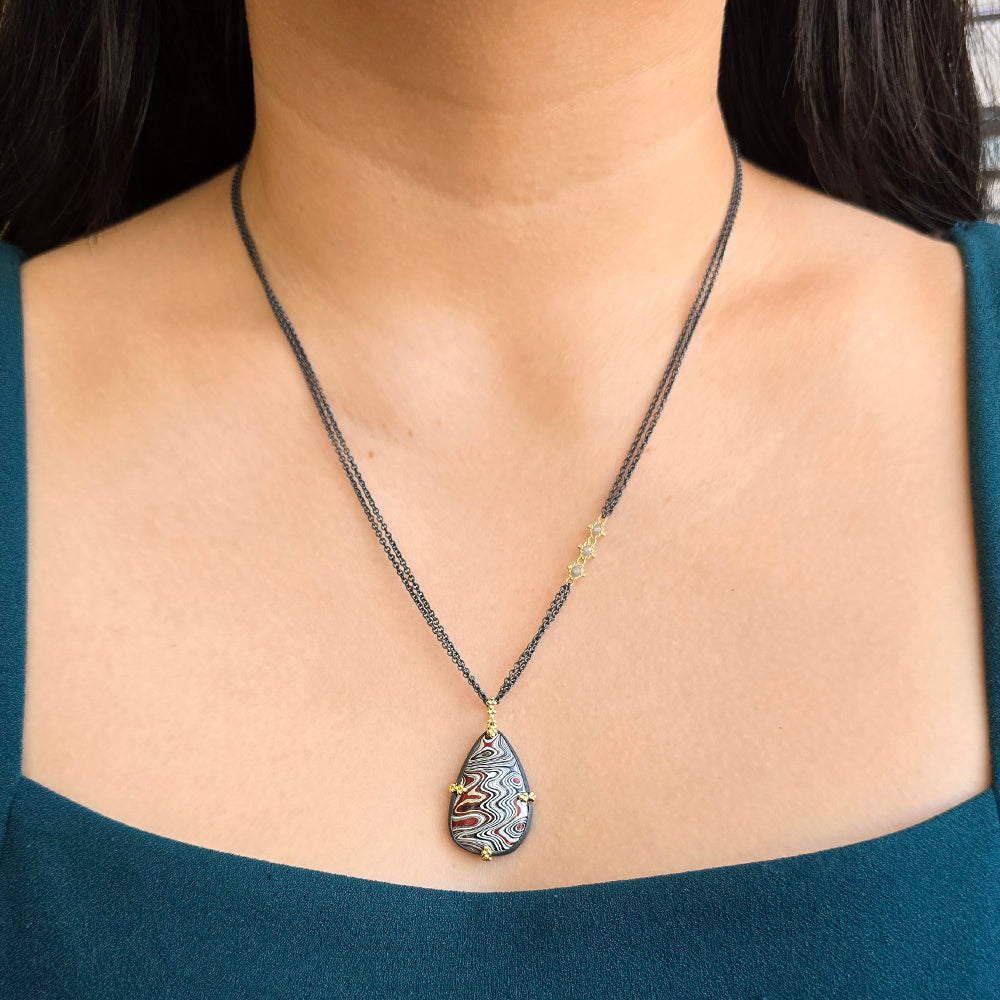 Close-up of layered Fordite pattern in oxidized silver and 18K gold setting