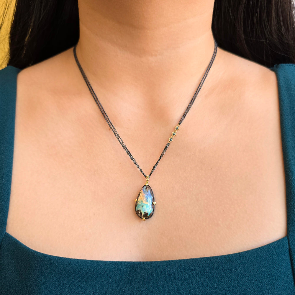 Woman wearing Northern Current boulder opal necklace by Amáli from Alara Jewelry