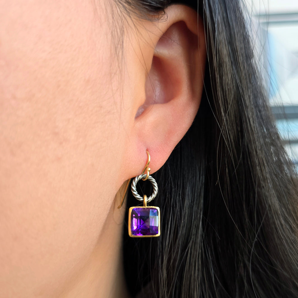 Woman wearing checkerboard-cut amethyst drop earrings with silver and gold from Alara Jewelry