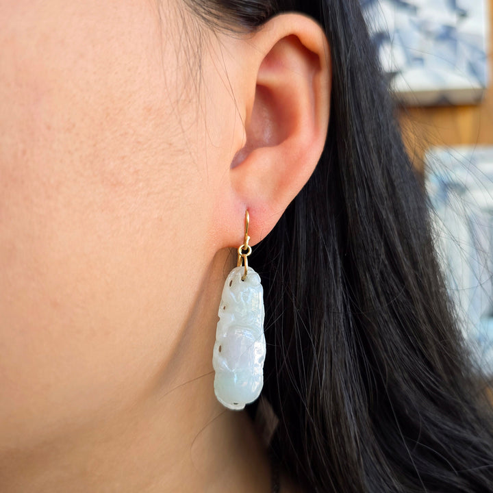Woman wearing vintage carved jadeite drop earrings in 18K gold from Alara Jewelry