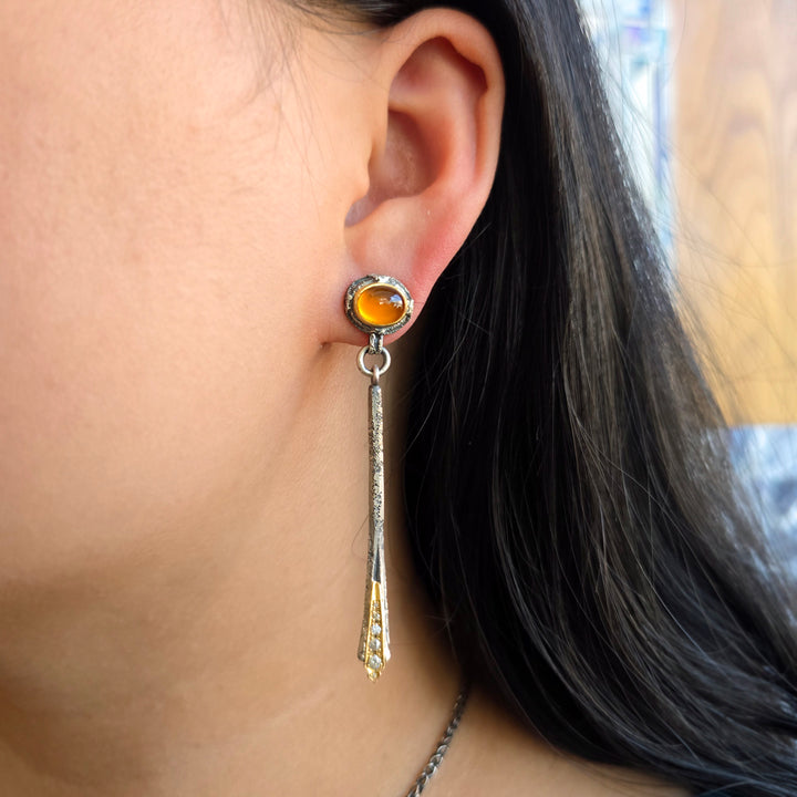 Woman wearing spessartite garnet drop earrings with silver and gold detailing from Alara Jewelry