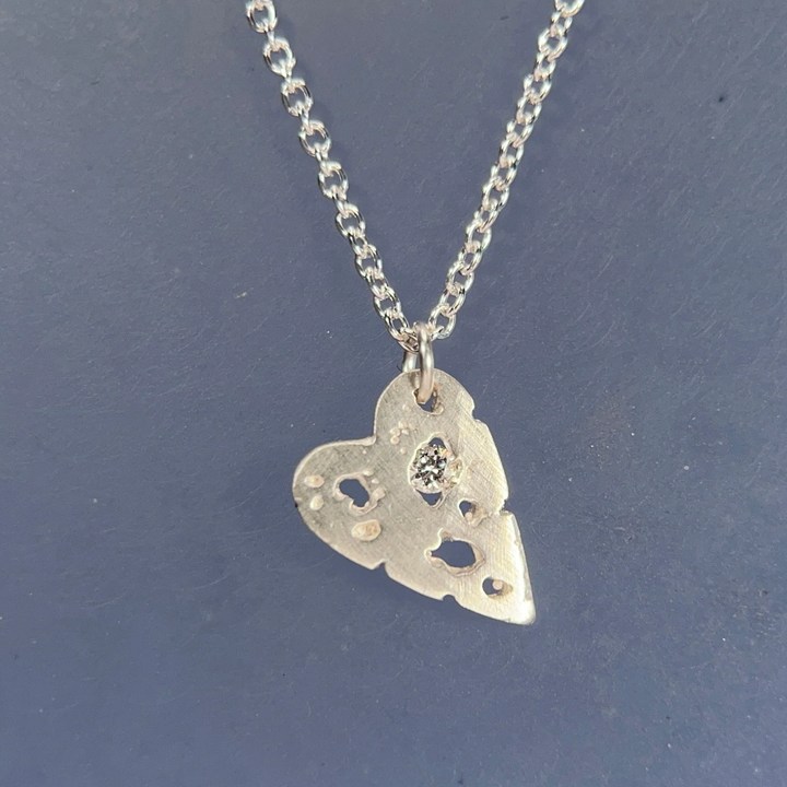 Silver heart-shaped pendant necklace on a dark blue background