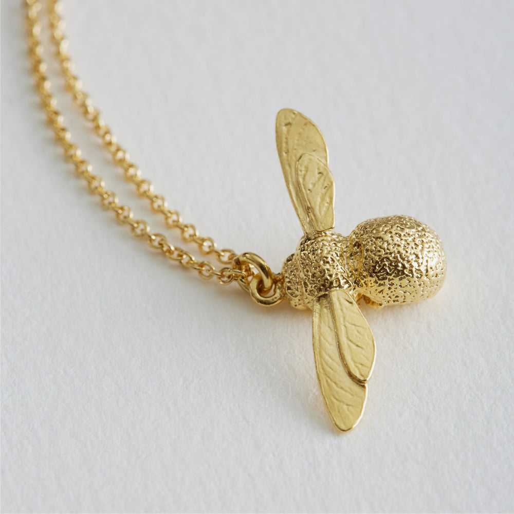 Close-up of hand-textured bee wings and body on gold vermeil pendant