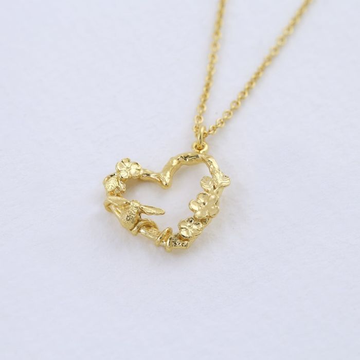 Close-up of hand-detailed bee and floral trellis on heart pendant