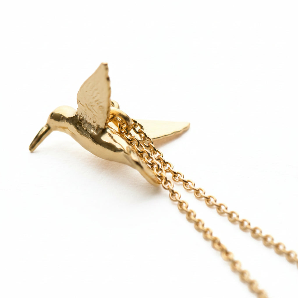 Close-up of hand-detailed hummingbird wings on gold vermeil pendant