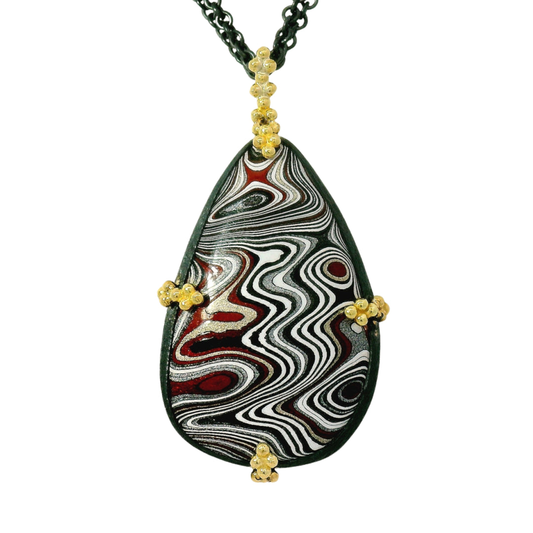 Close-up of layered Fordite pattern in oxidized silver and 18K gold setting