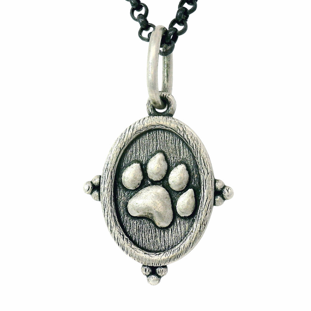 Silver pendant with a paw print design on a white background