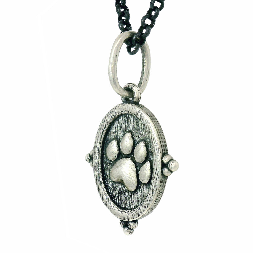 Silver pendant with paw print design on a white background
