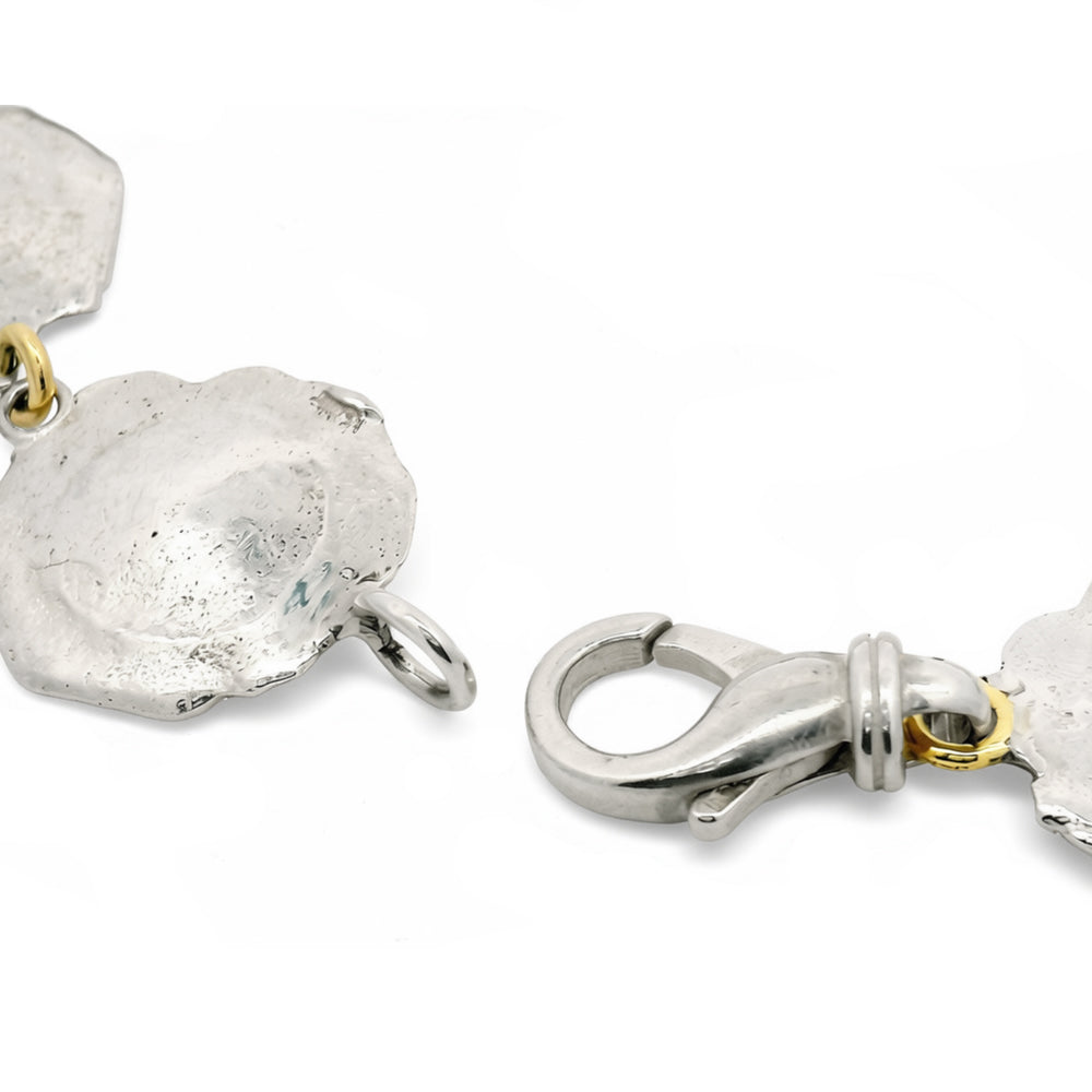 Close-up of irregular textured silver disc links with gold connections