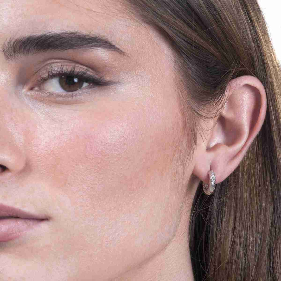 Woman wearing Lava Collection textured silver huggie hoops from Alara Jewelry