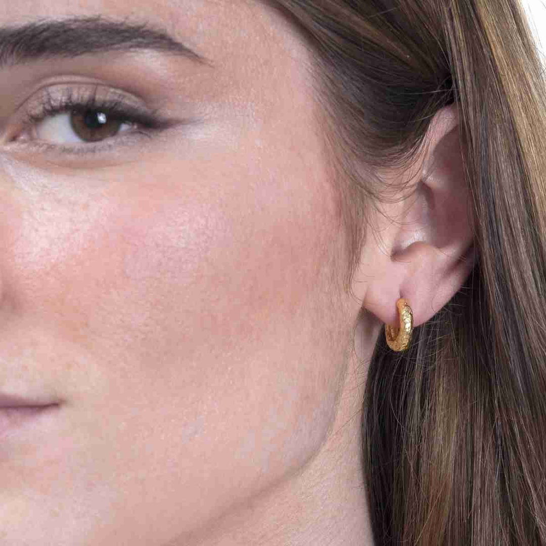 Woman wearing Lava Collection textured gold vermeil huggie hoops from Alara Jewelry