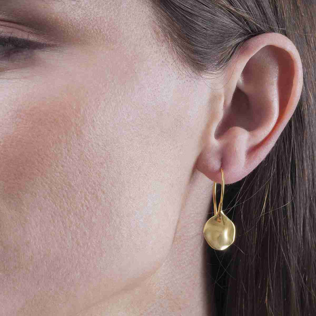 Woman wearing sculptural gold vermeil drop earrings by Jorge Revilla from Alara Jewelry