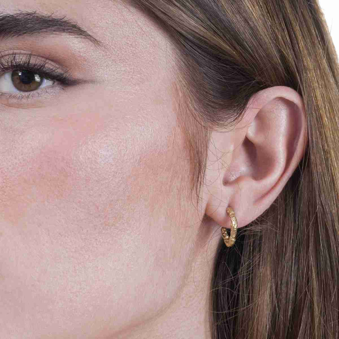Woman wearing Lava Collection textured gold vermeil hoop earrings from Alara Jewelry
