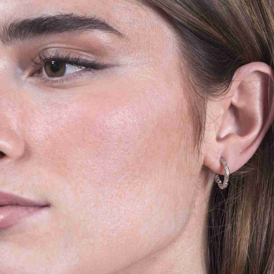 Woman wearing Lava Collection textured sterling silver hoop earrings from Alara Jewelry