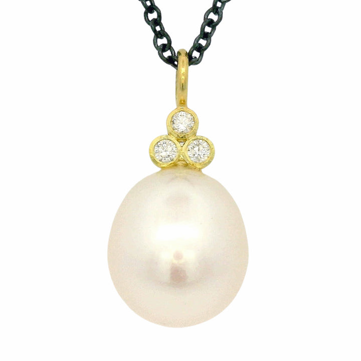 Close-up of pearl drop necklace with three round brilliant-cut diamonds
