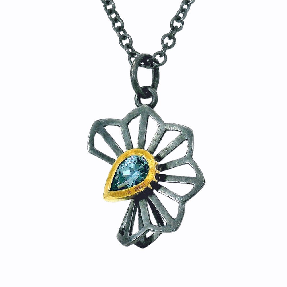 Close-up of pear-shaped blue Montana sapphire in gold bezel on floral pendant