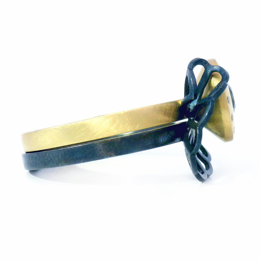 Close-up of oxidized silver origami fold ring nested beside gold sapphire ring