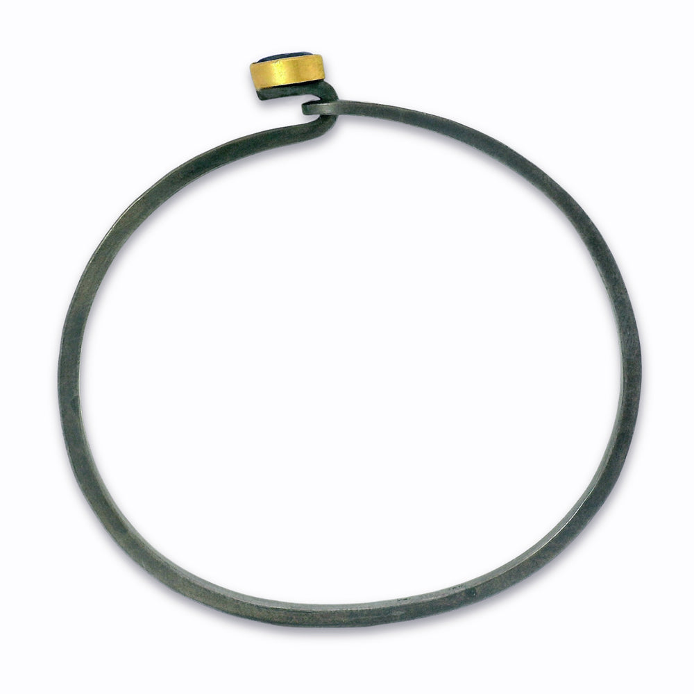 Close-up of pear-cut blue Montana sapphire set in gold bezel on silver bracelet