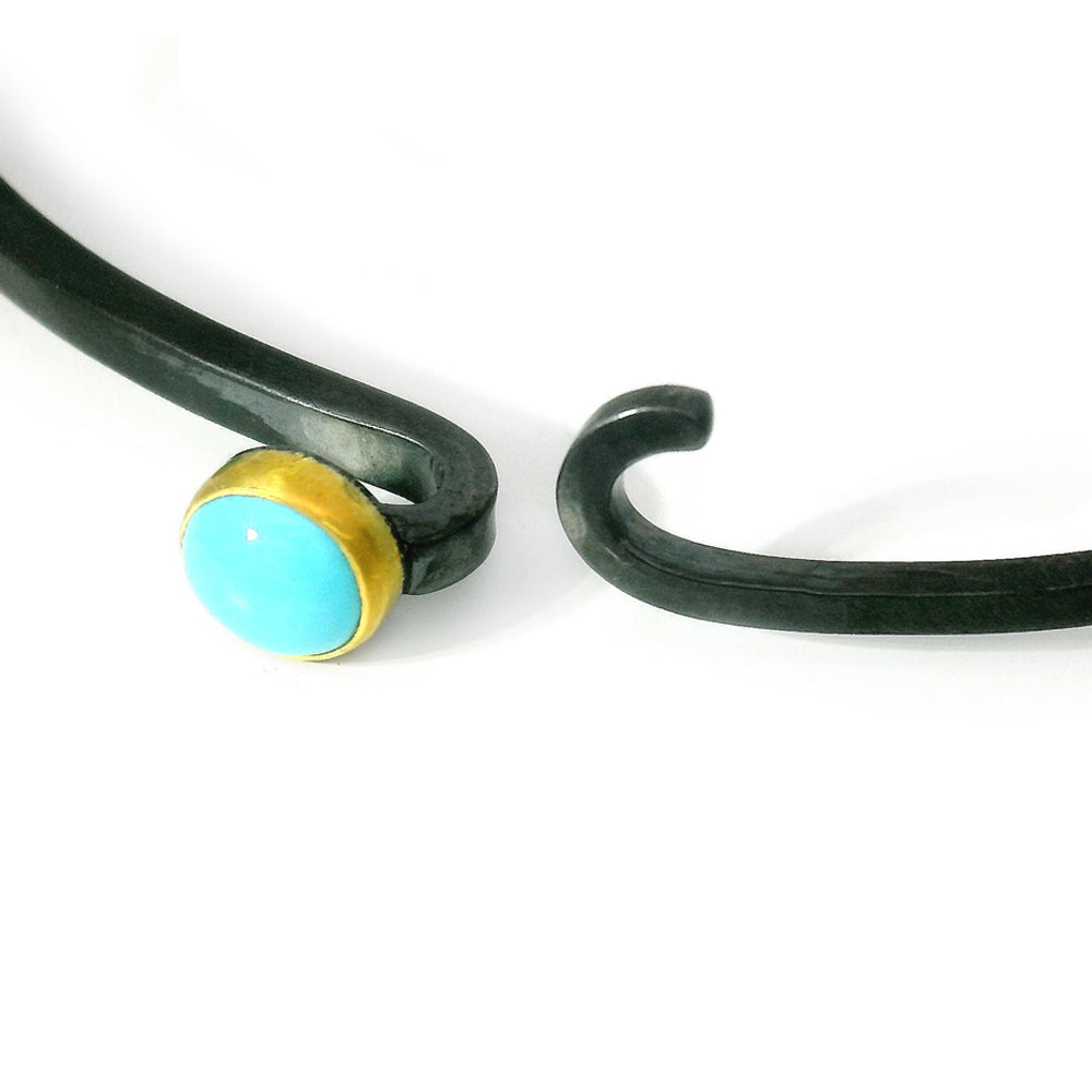 Close-up of round turquoise cabochon set in gold bezel on silver hook bracelet