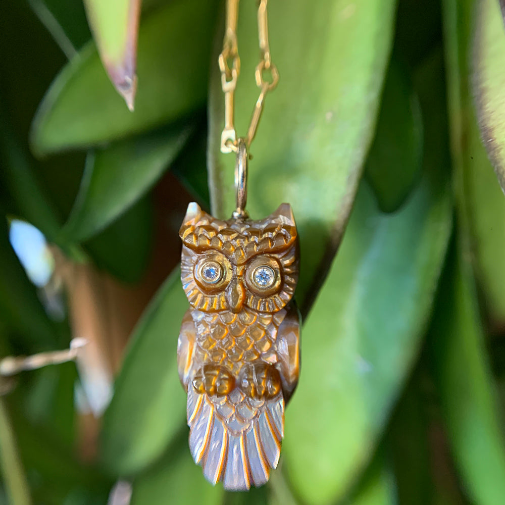 Close-up of hand-carved feather detail and diamond eyes on owl pendant