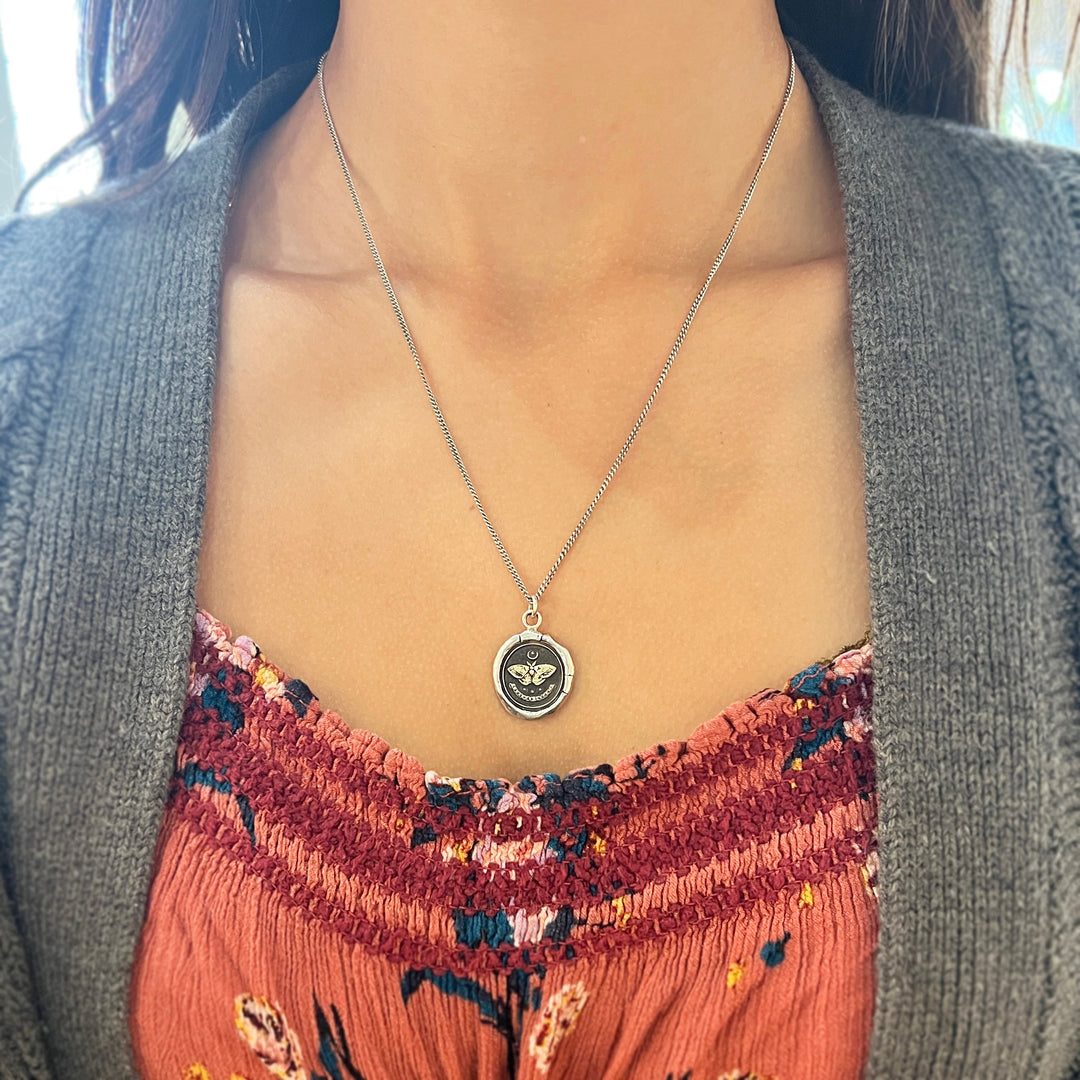 Woman wearing Seek the Light moth talisman necklace by Pyrrha from Alara Jewelry