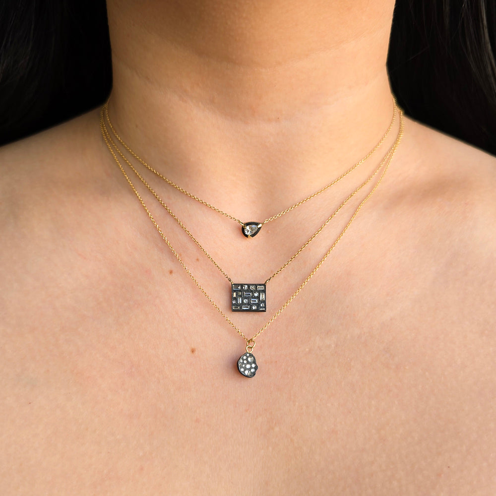 Woman wearing City Lights diamond pendant necklace with other pendants from Alara Jewelry