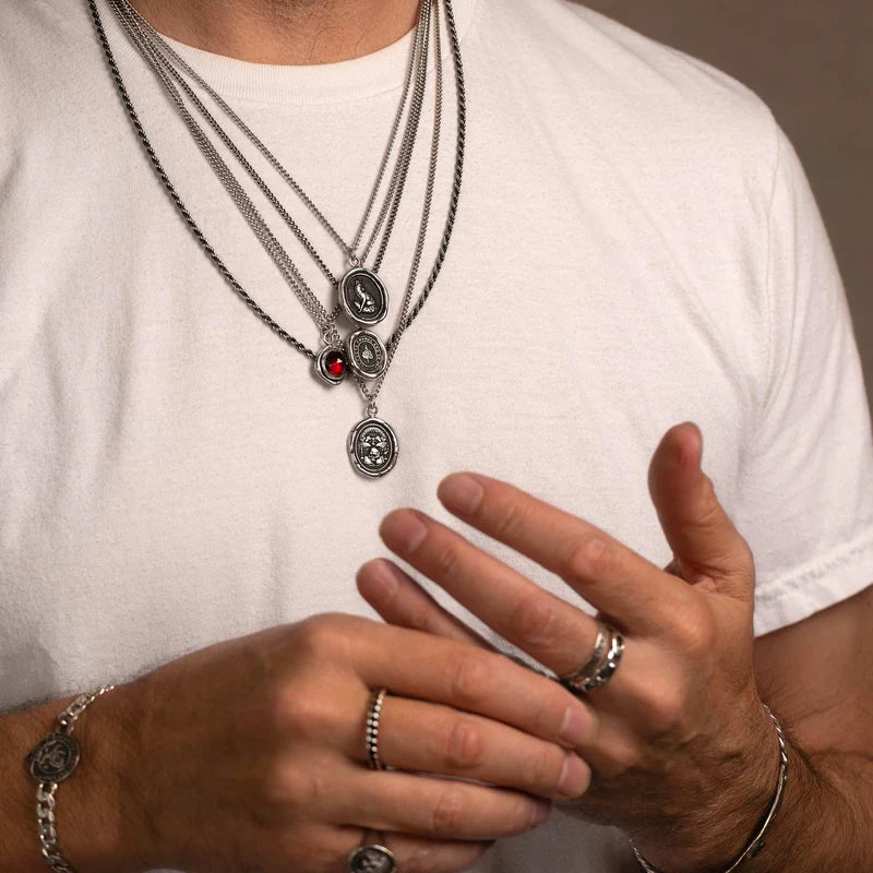 Man in a white shirt wearing several talisman necklaces.