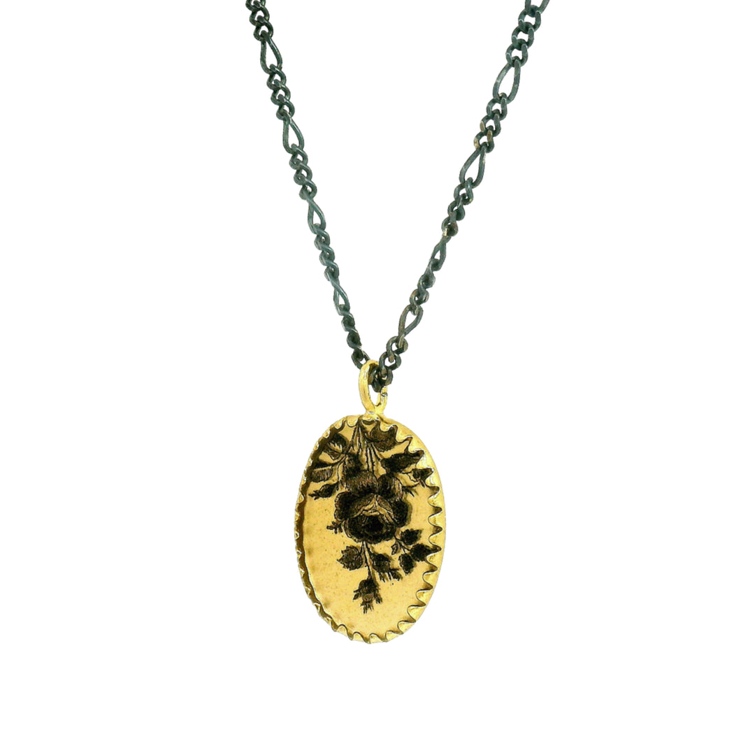 Close-up of detailed rose and foliage illustration on oval pendant